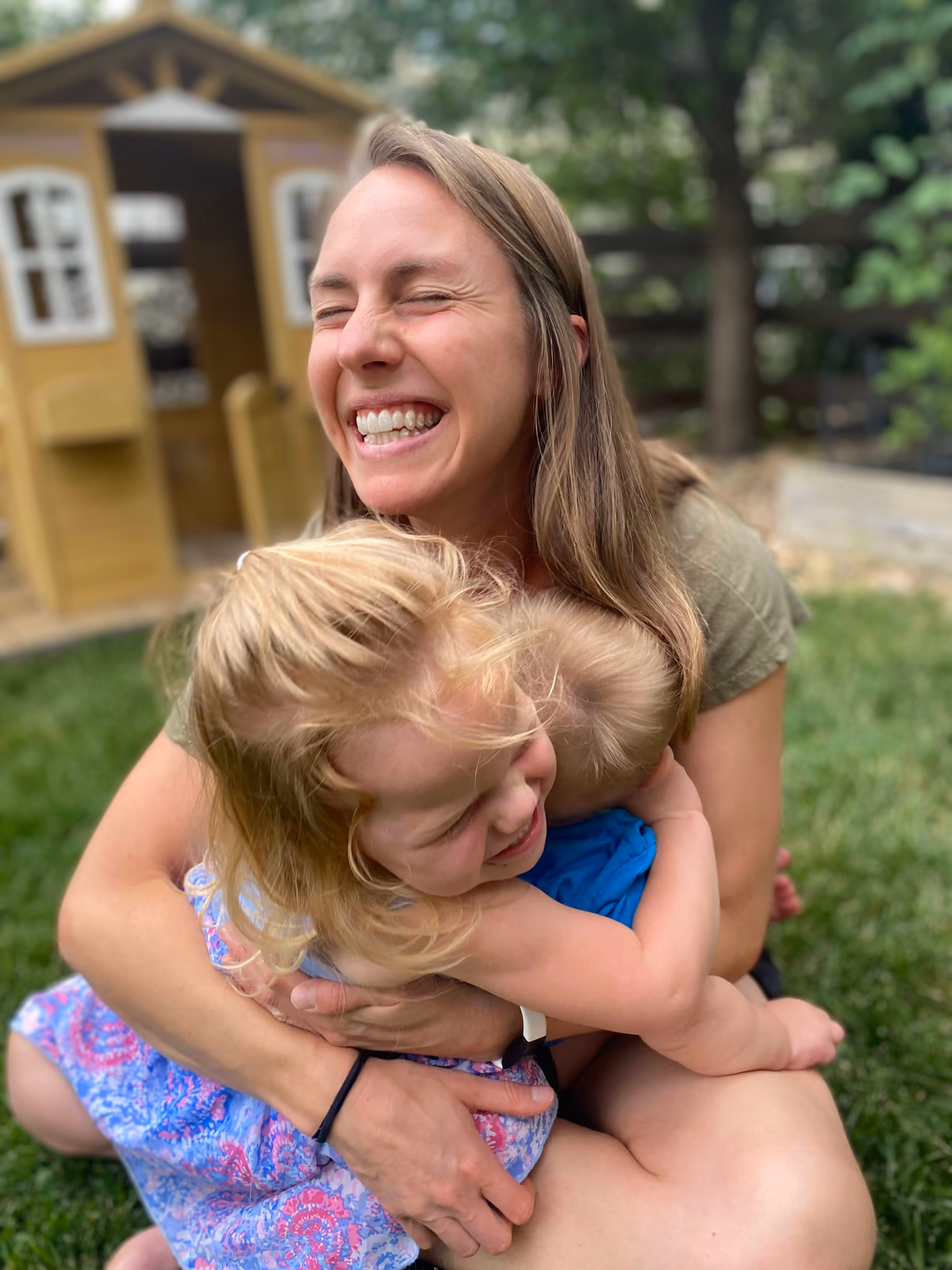 Lizi laughing as two of her children hug her outside