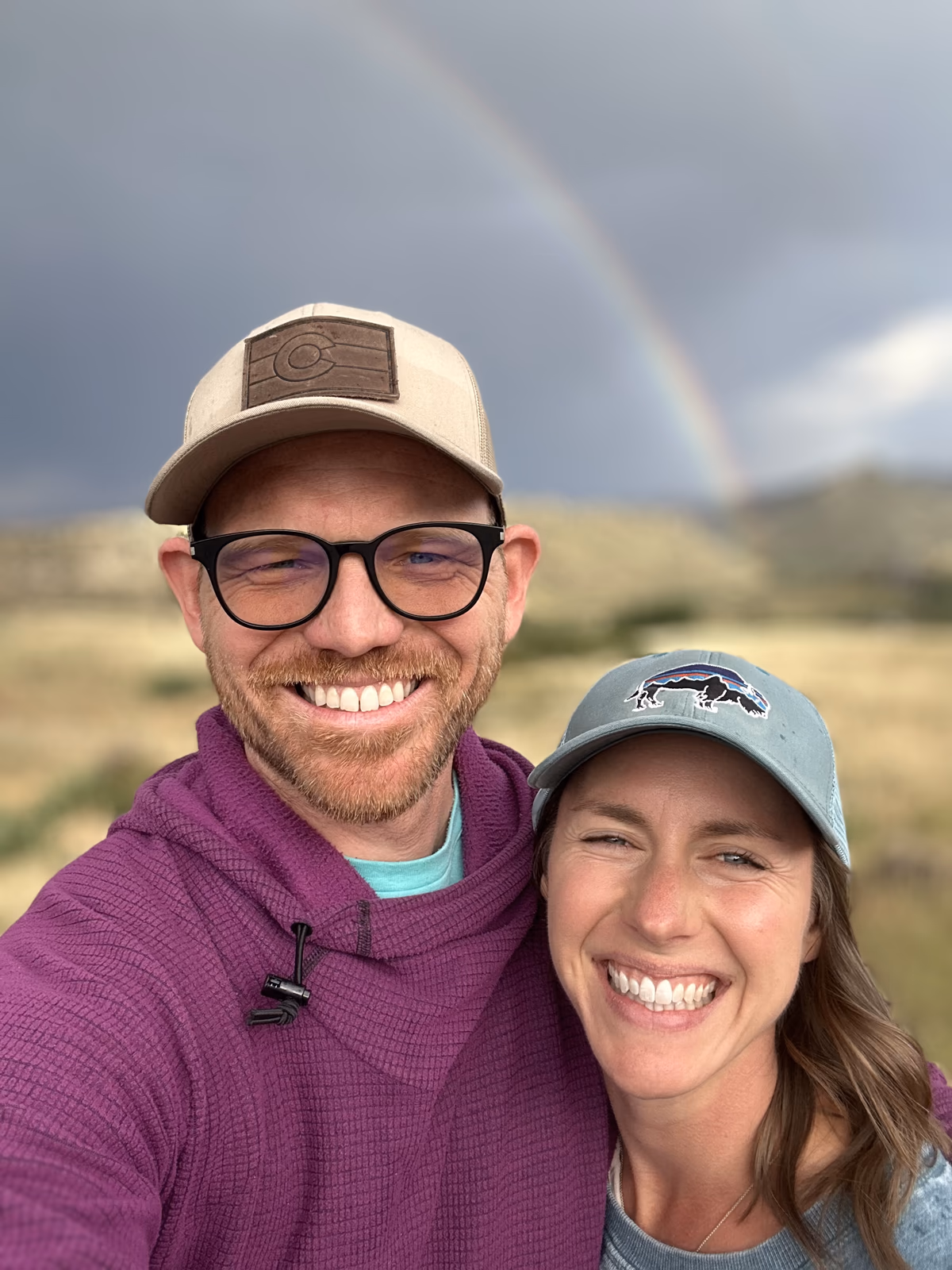 Lizi and Matt smiling together beneath a rainbow