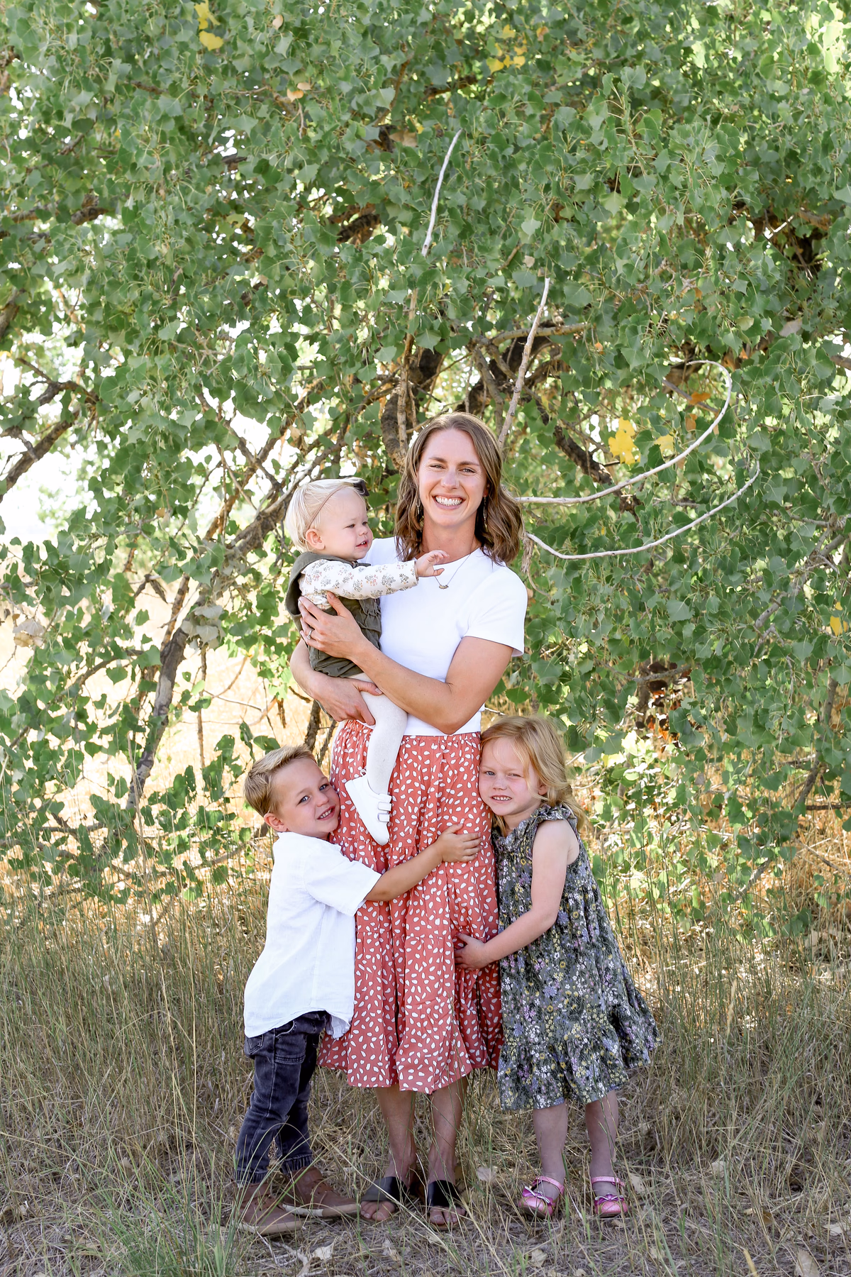 Lizi smiling outdoors with her three children
